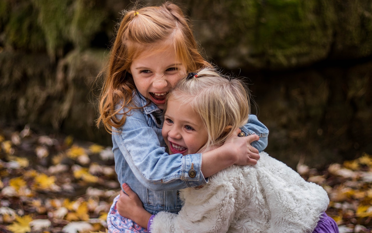 Dwie dziewczynki bawią się pośród liści