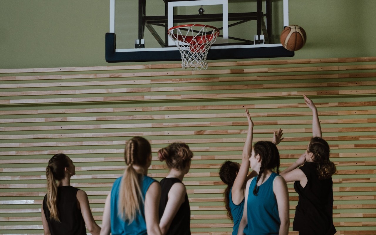Młodzież gra w koszykówkę na sali gimnastycznej