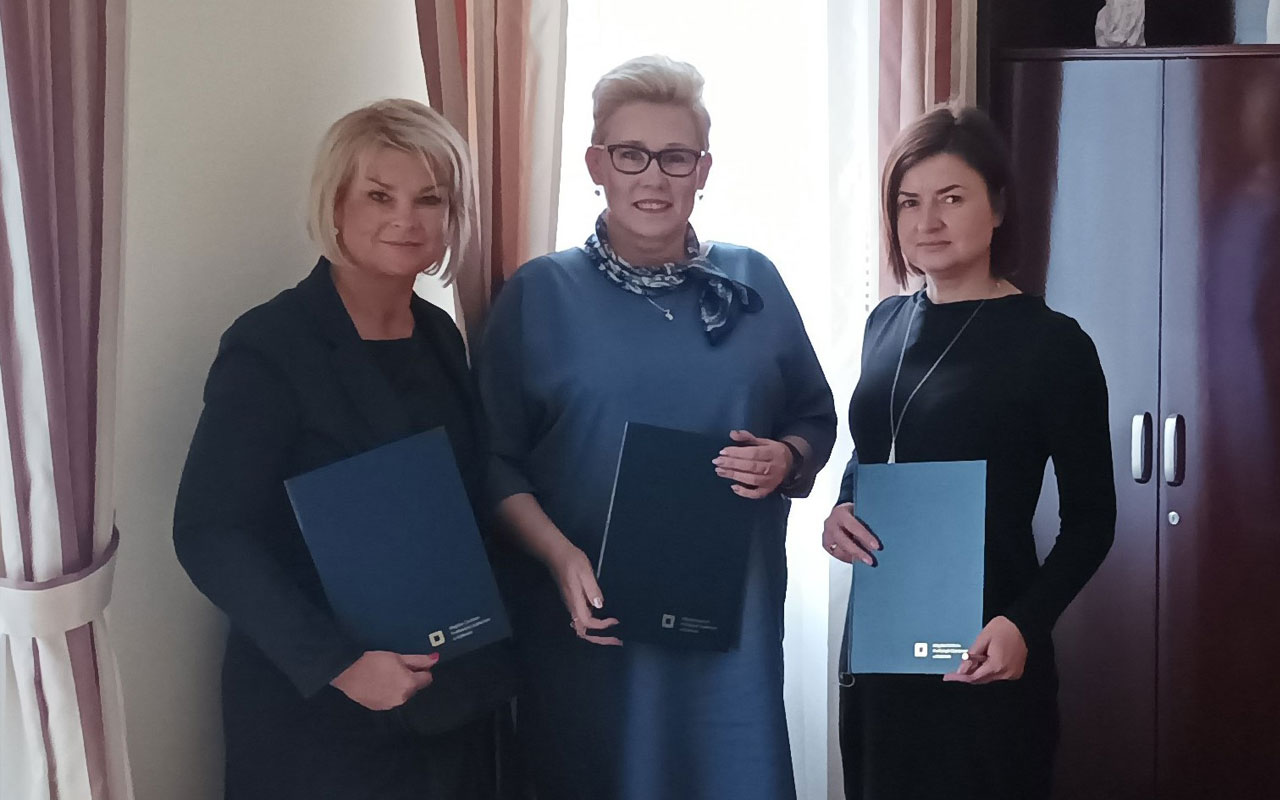 Pani Agnieszka Bogusz, Pani Marta Rzadkowska oraz Pani Karolina Załęga pozują wspólnie do zdjęcia trzymając w dłoniach dokumenty porozumienia