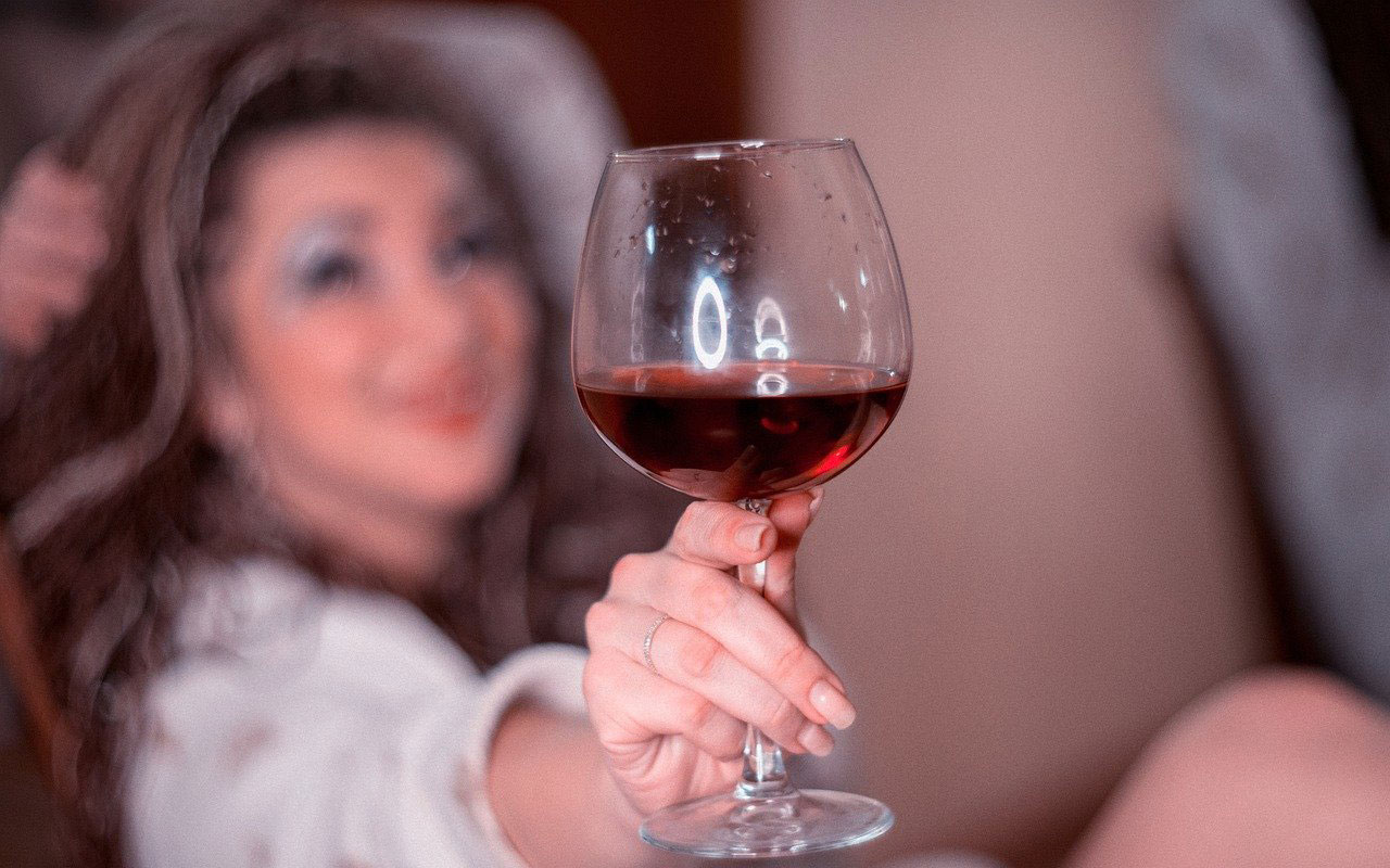 kobieta trzymająca w dłoni kieliszek z czerwonym winem