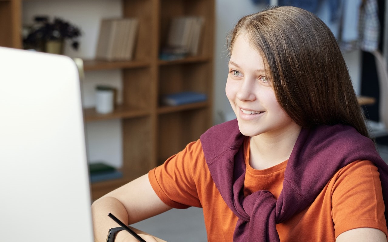 Uśmiechnięta dziewczynka patrzy w ekran komputera