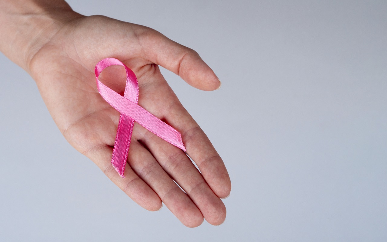 różowa wstążka symbolizująca raka piersi położona na wewnętrznej stronie dłoni